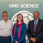 Ralph Ferraro, Lisa Milani, and Amitabh Varshney pose in front of the UMD Science backdrop at the event.