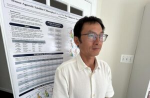 Guangming Zheng stands in front of his poster.