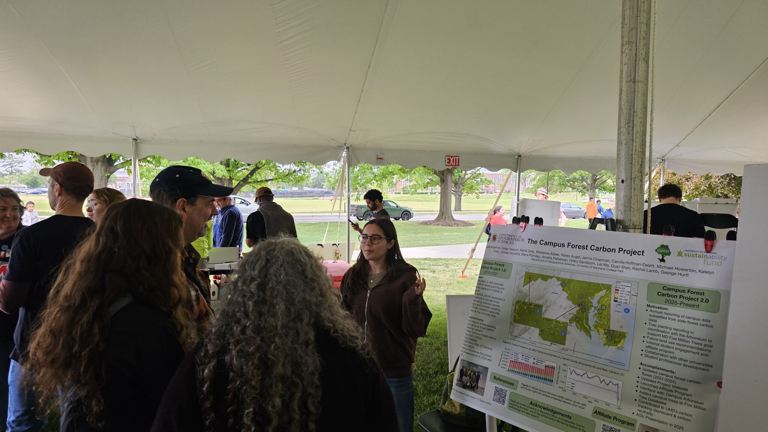 A student presents her poster to a group of attendees.