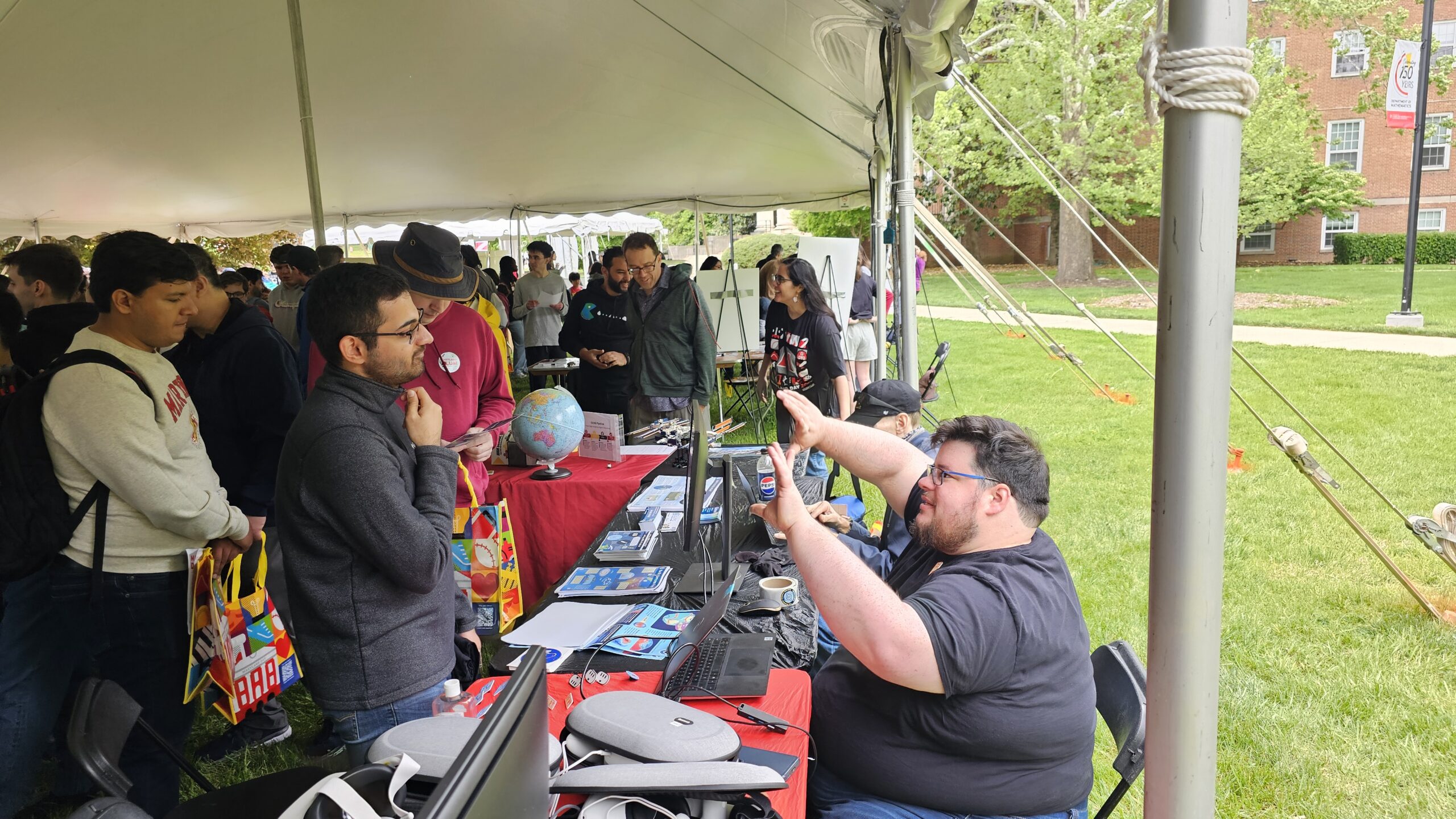 A scientist speaks to a group of attendees behind a booth