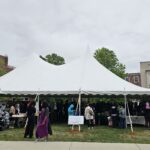 A large white tent on the grass in front of the Glenn L. Martin building, hosting several CMNS departments
