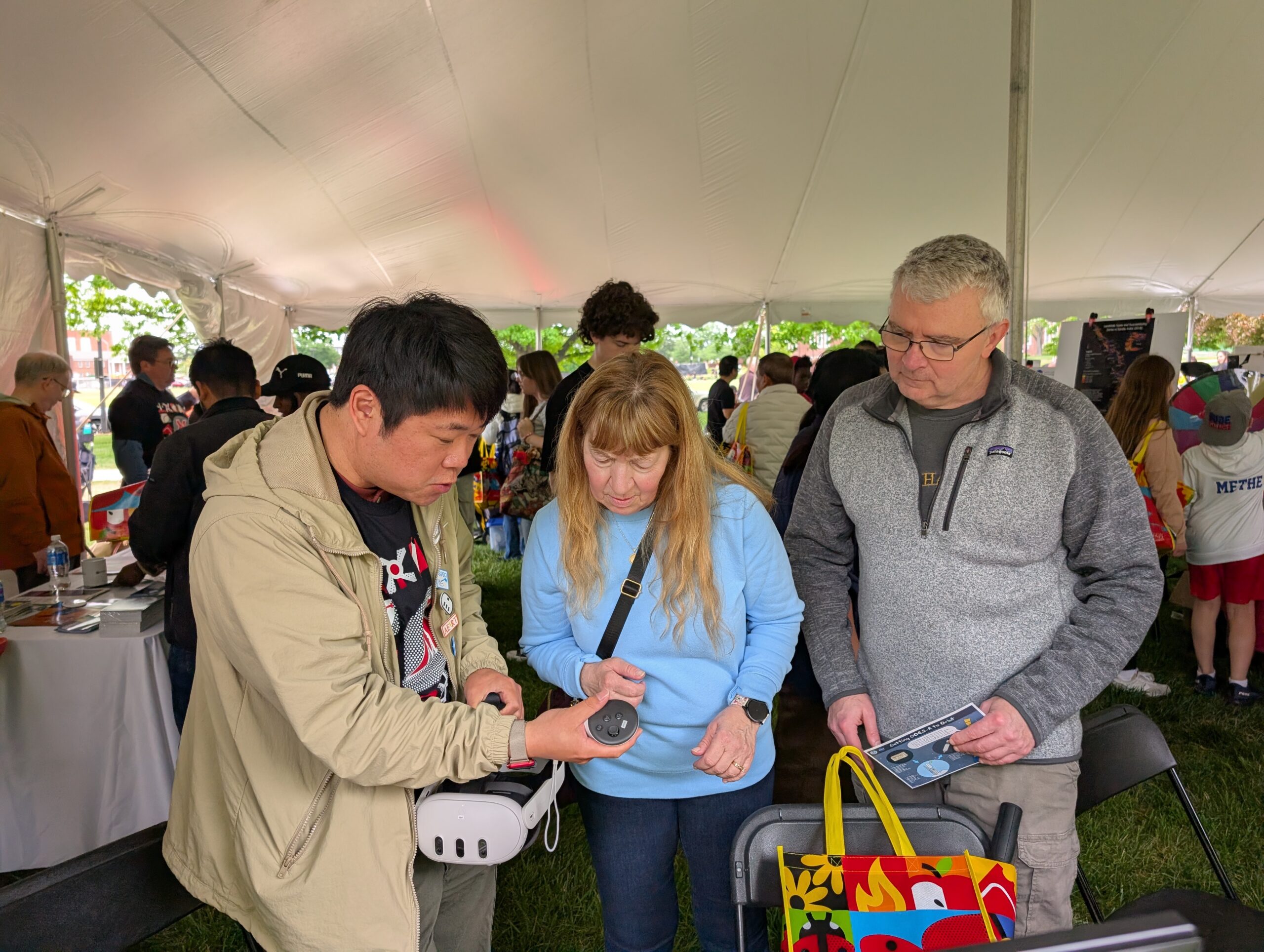A scientist shows two attendees VR equipment