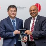 Two men pose happily holding an award